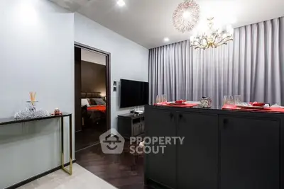 Modern living room with elegant decor and open view to bedroom, featuring stylish lighting and sleek furniture.