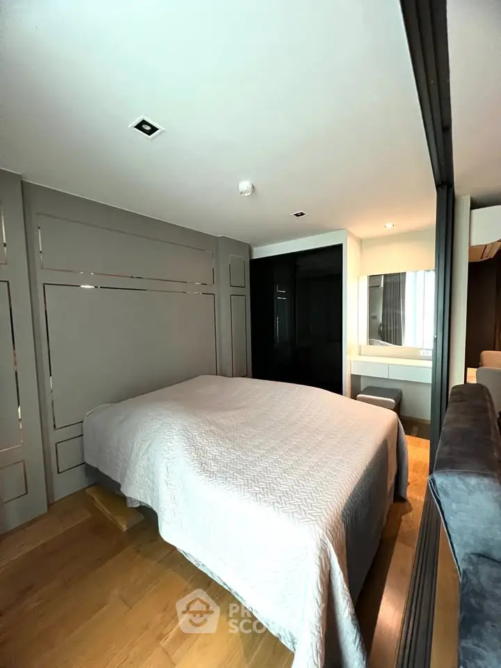 Modern bedroom with stylish decor and wooden flooring, featuring a cozy bed and elegant lighting.