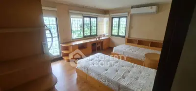 Spacious bedroom with twin beds, large windows, and built-in wooden furniture.