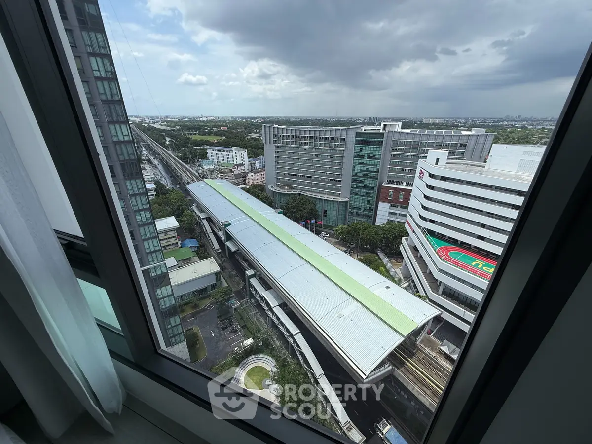 Stunning cityscape view from high-rise apartment window overlooking modern urban architecture.