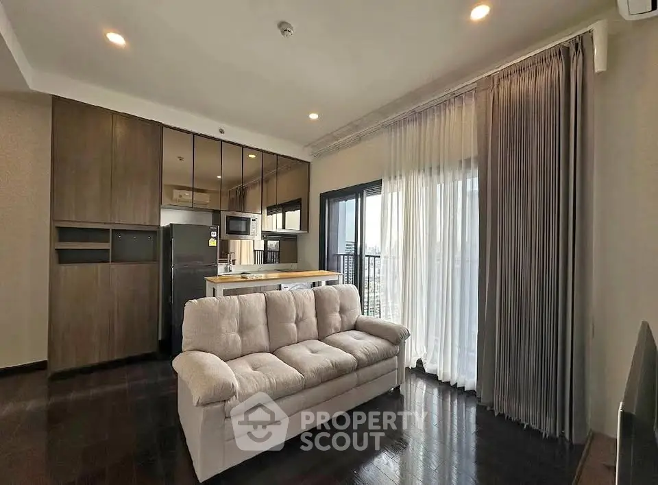Modern living room with sleek kitchen and large windows offering city views.