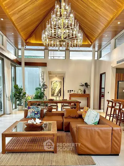 Luxurious living room with high ceiling, elegant chandelier, and stylish leather furniture.
