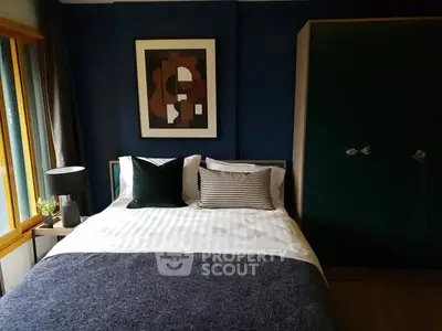Cozy bedroom with modern decor and large window for natural light.