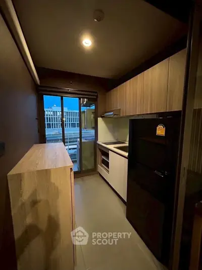 Modern kitchen with sleek appliances and wooden cabinetry, featuring a large refrigerator and ample counter space.