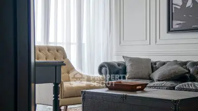 Elegant living room with classic sofa and armchair, featuring stylish decor and natural light.