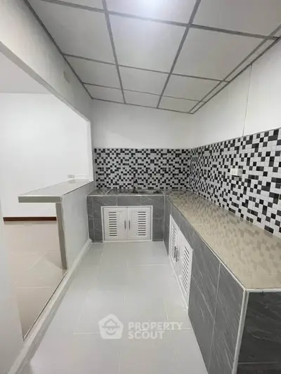 Modern kitchen with stylish black and white tile backsplash and open layout.
