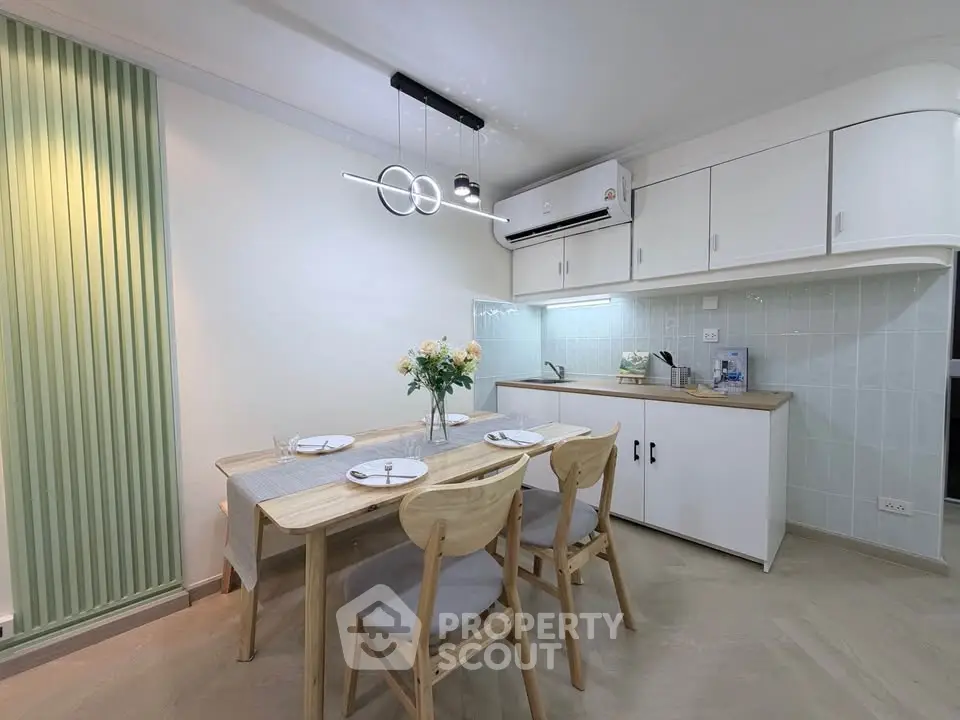 Modern kitchen with dining area, featuring sleek cabinets and stylish lighting.