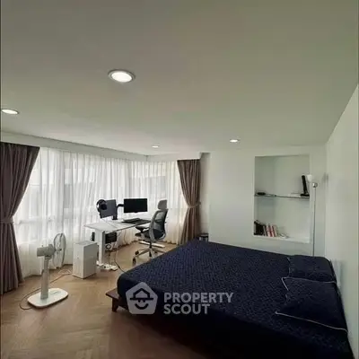 Modern bedroom with study area, featuring a sleek desk and large windows for natural light.