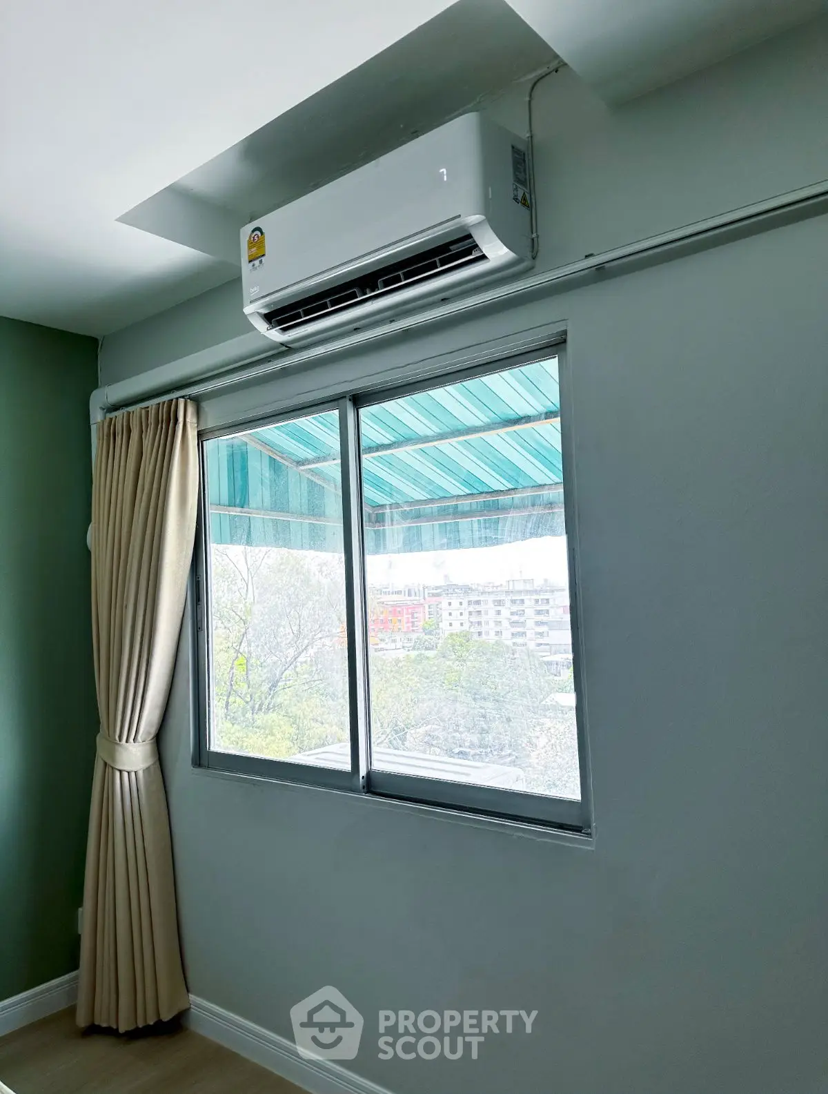 Bright room with large window and air conditioning unit, offering a city view.