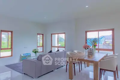 Spacious modern living room with large windows and elegant dining area.