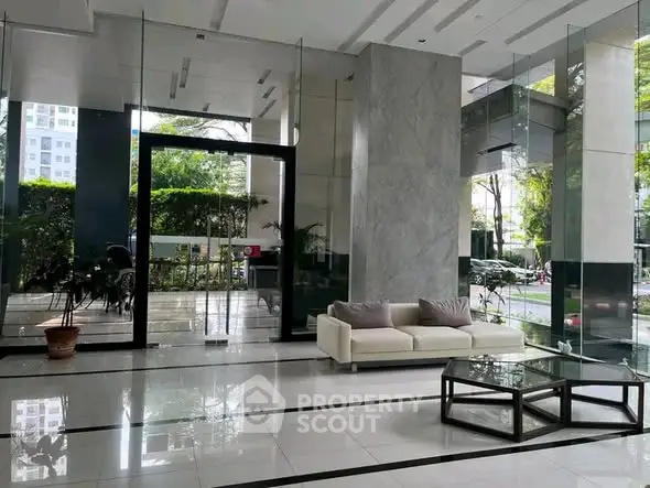 Luxurious building entrance with modern glass design and elegant seating area.