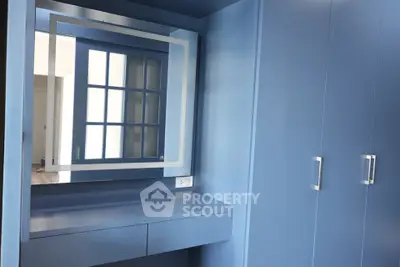 Modern blue wardrobe with built-in mirror and sleek handles in a stylish bedroom.
