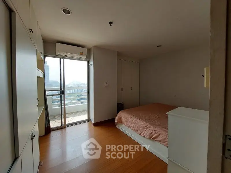 Cozy bedroom with balcony access and ample natural light in modern apartment.