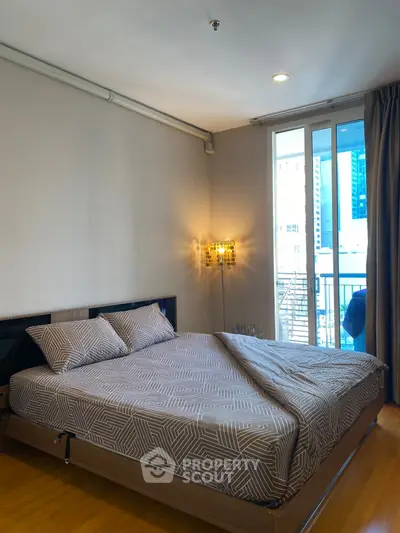 Modern bedroom with stylish decor and city view balcony access.