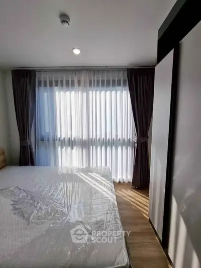 Bright bedroom with large window and modern curtains, showcasing natural light and cozy ambiance.