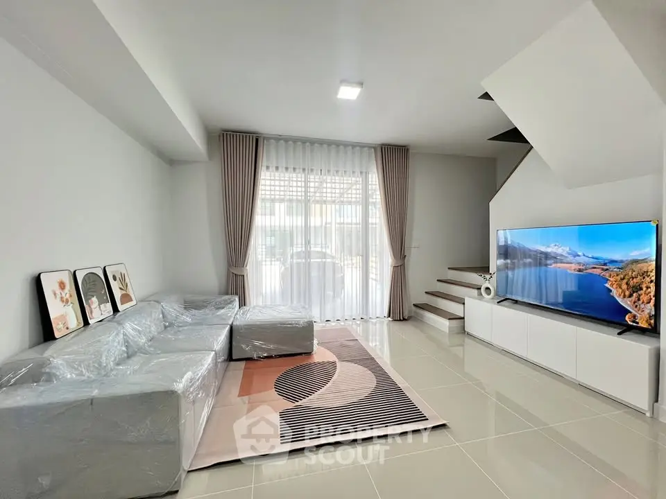Modern living room with sleek design, large TV, and stylish sofa under natural light.