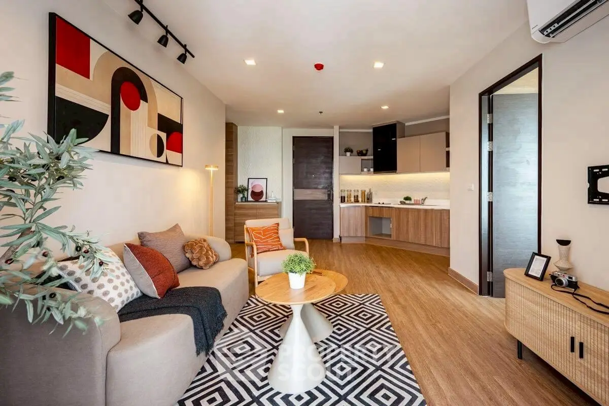 Modern living room with stylish decor and open kitchen layout, featuring cozy seating and contemporary artwork.