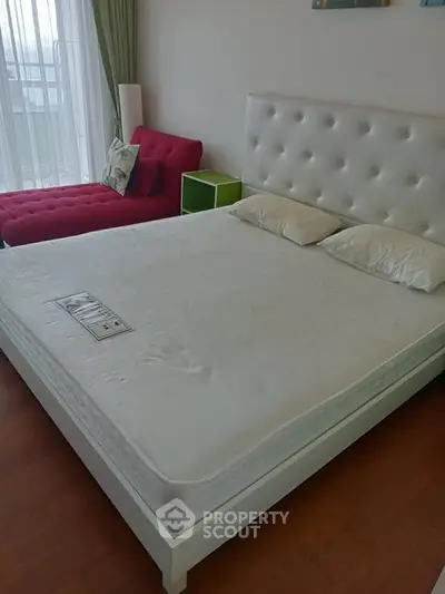 Spacious bedroom with modern white bed and vibrant red chaise lounge