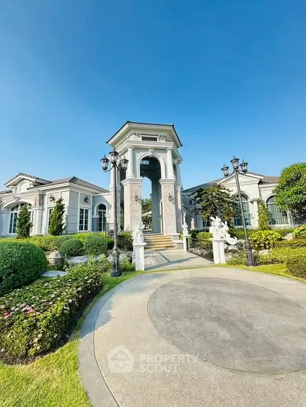 Luxurious mansion entrance with elegant landscaping and classic architectural design.