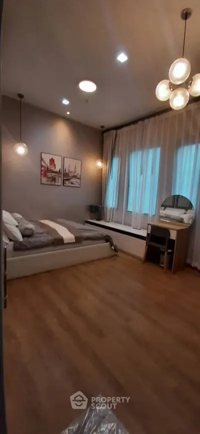 Spacious bedroom with modern decor and large windows for natural light.