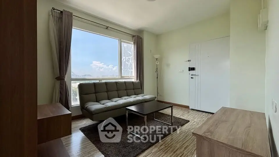 Bright living room with modern sofa and large window offering scenic views.