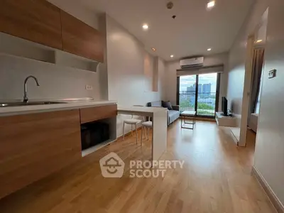 Modern open-plan living room with kitchen, featuring wood flooring and city view balcony.