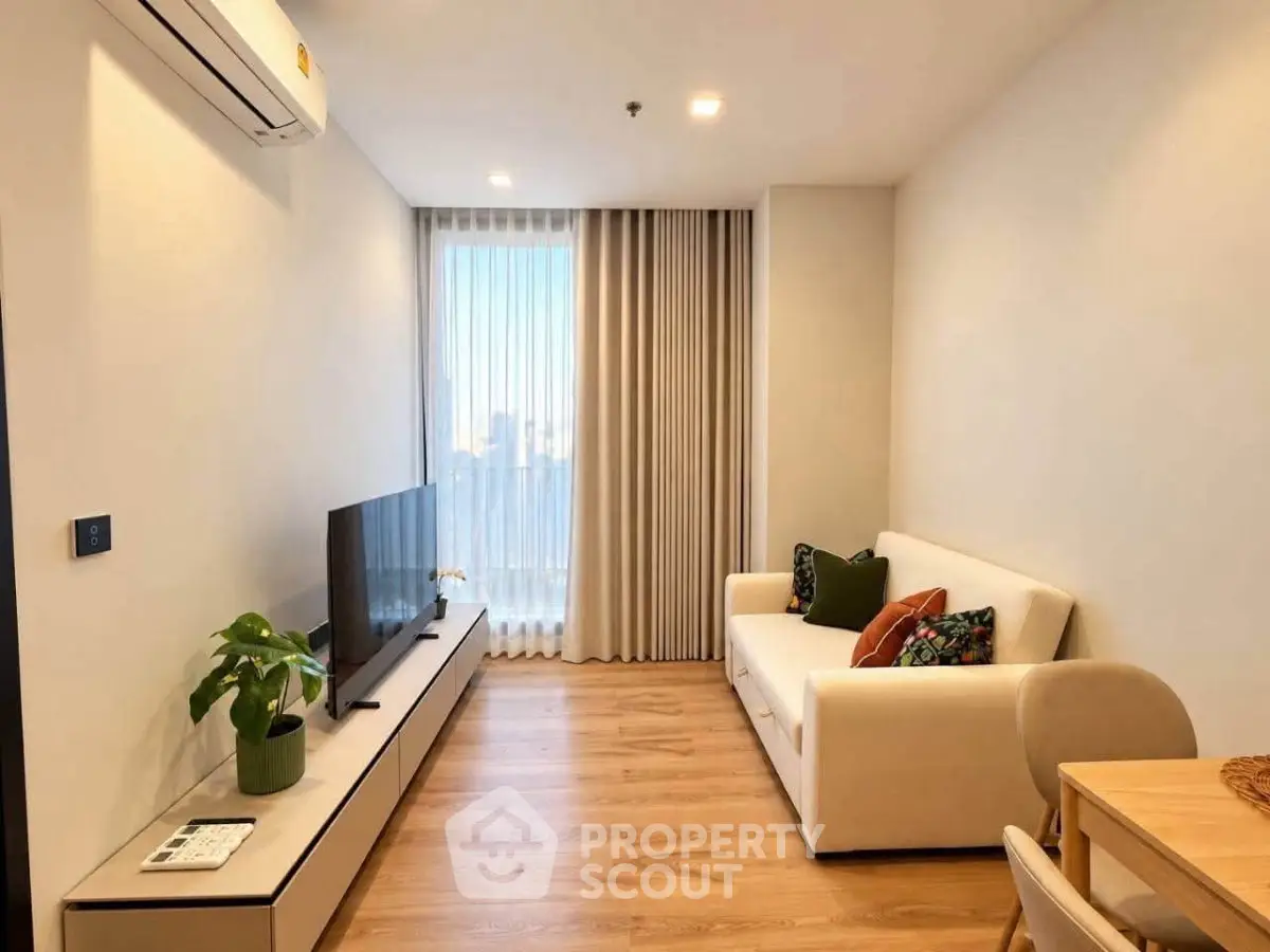 Modern living room with sleek furniture and large window, perfect for urban living.