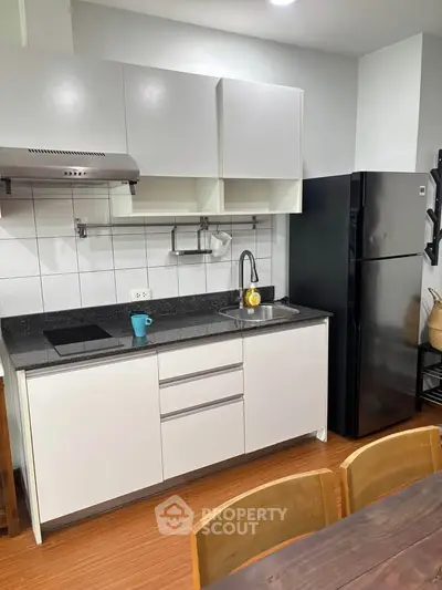 Modern kitchen with sleek cabinets and black appliances in a cozy apartment.