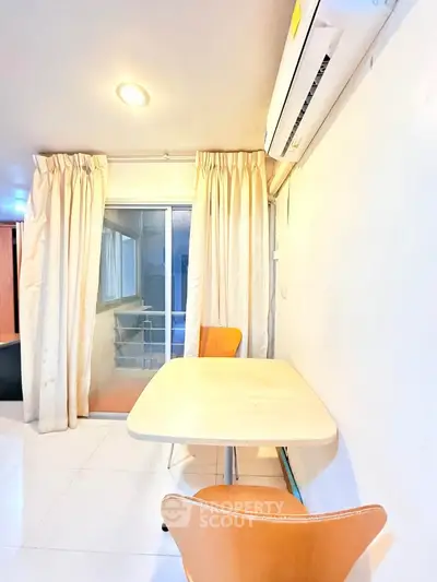Bright dining area with modern table and chairs, featuring large window and air conditioning.