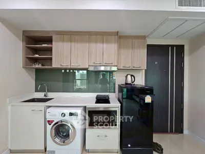 Modern kitchen with washing machine and sleek appliances in compact layout.