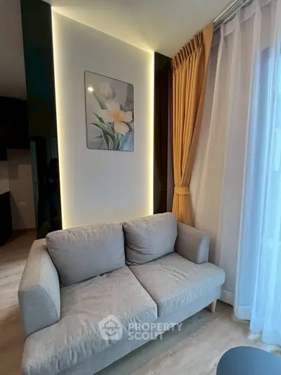 Modern living room with cozy gray sofa and elegant lighting, featuring stylish curtains and wall art.
