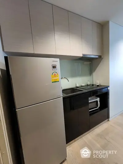 Modern kitchen with sleek cabinets and stainless steel fridge in stylish apartment.