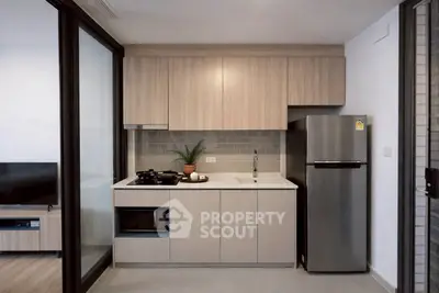 Modern kitchen with sleek cabinetry and stainless steel fridge in a stylish apartment.