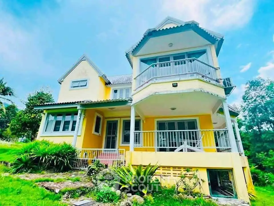 Charming yellow two-story house with lush garden and spacious balcony