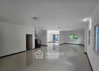 Spacious open-plan living room with glossy floors and ample natural light.