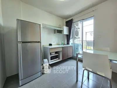 Modern kitchen with stainless steel fridge and balcony access in a bright apartment.