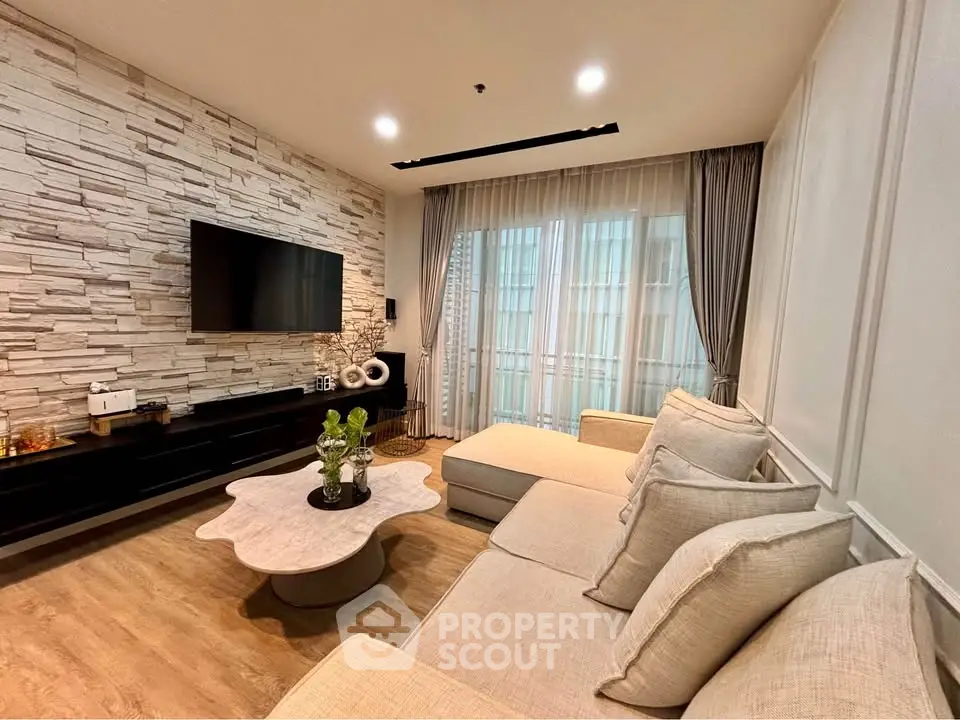 Modern living room with stylish stone wall, large sofa, and sleek TV setup.