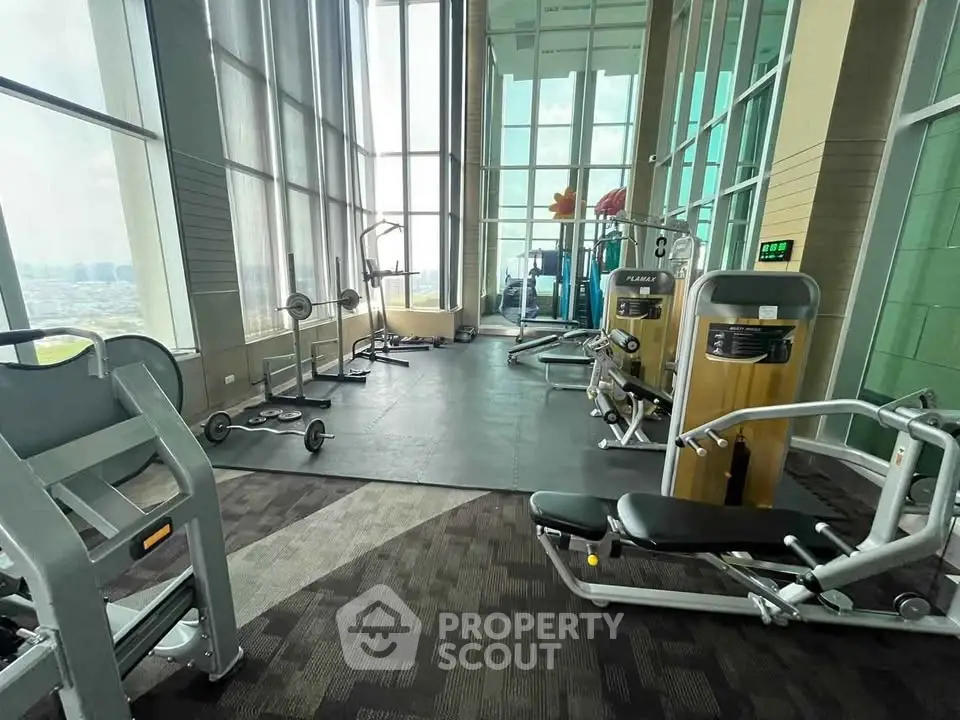 Spacious gym with modern equipment and floor-to-ceiling windows offering a stunning view.