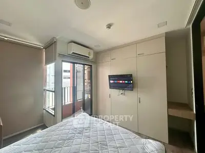 Modern bedroom with balcony access and wall-mounted TV in a stylish apartment.