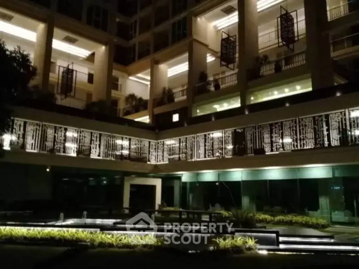 Stunning modern building exterior with illuminated balconies and landscaped garden at night.