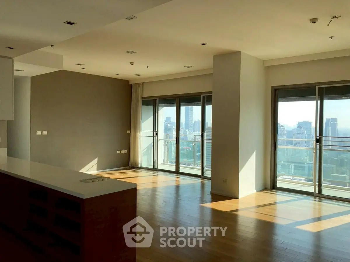 Spacious modern living room with large windows offering stunning city views and abundant natural light.