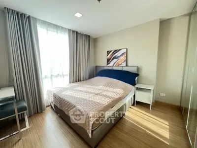 Modern bedroom with natural light, stylish decor, and wooden flooring in a cozy apartment.