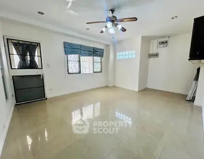Spacious empty room with ceiling fan and tiled floor, perfect for customization.