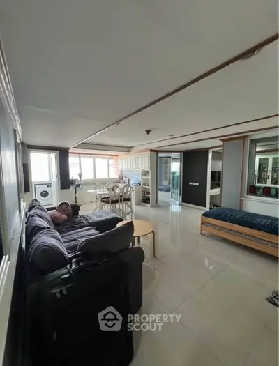 Spacious living room with modern decor and natural light, featuring a cozy seating area and dining space.