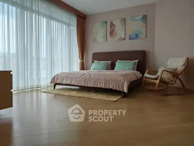 Spacious bedroom with large windows and elegant decor, featuring a cozy bed and modern furnishings.