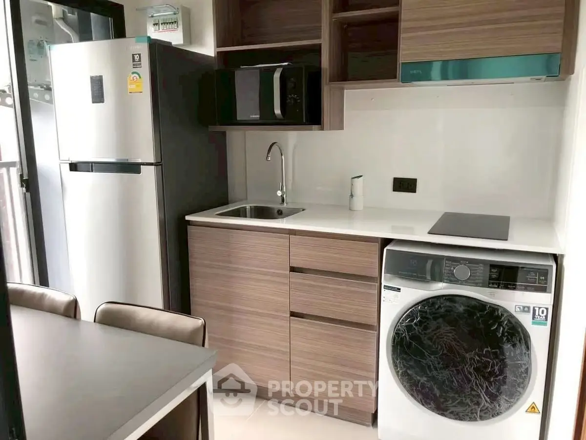 Modern compact kitchen with washing machine and sleek appliances in urban apartment