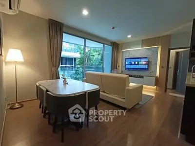 Modern living room with open layout and large windows overlooking greenery.