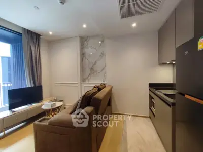 Modern living room with sleek kitchen in open layout, featuring stylish decor and natural light.