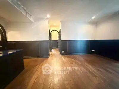 Spacious interior with elegant wood flooring and classic wainscoting, perfect for stylish living.