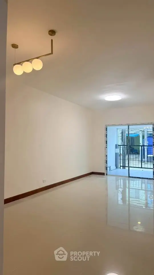 Spacious living room with modern lighting and large balcony access.